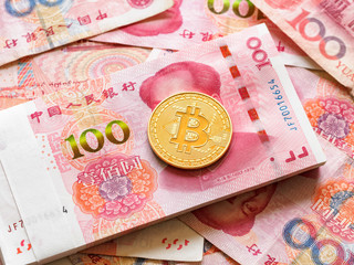 Close up image of a golden Bitcoin on piles of 100 yuan or renminbi banknotes, Financial concept, Chinese Currencies.