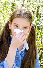 Little girl has allergy to spring blossoming and blowing her nose