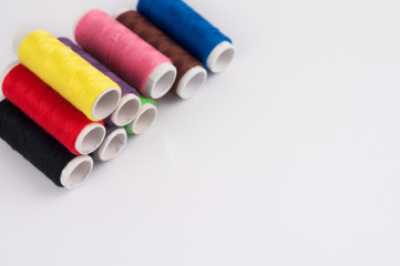 Heap of bobbins of new colorful threads on white background