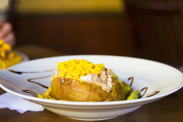 Stuffed potato with tuna and sweetcorn on white plate selective focus
