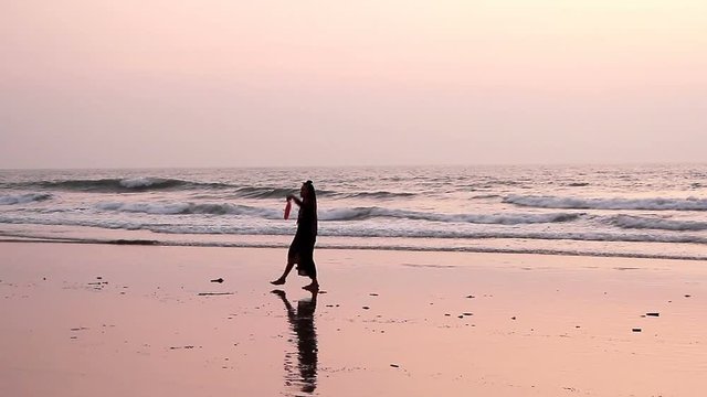 Unidentified woman dancing with fan on the beach. 