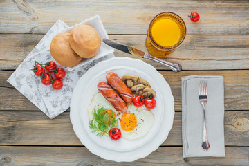 English breakfast with fried eggs, sausages, mushrooms, grilled tomatoes