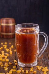A mug of home-made kvass with raisin on a dark wooden background