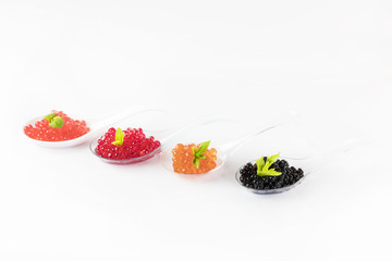 Plastic spoons with fish caviar on a white background. 