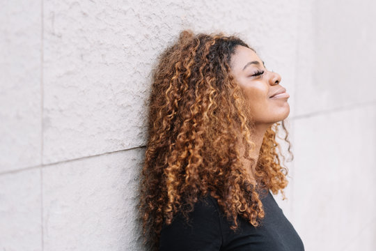 Dreamy black woman leaning against wall