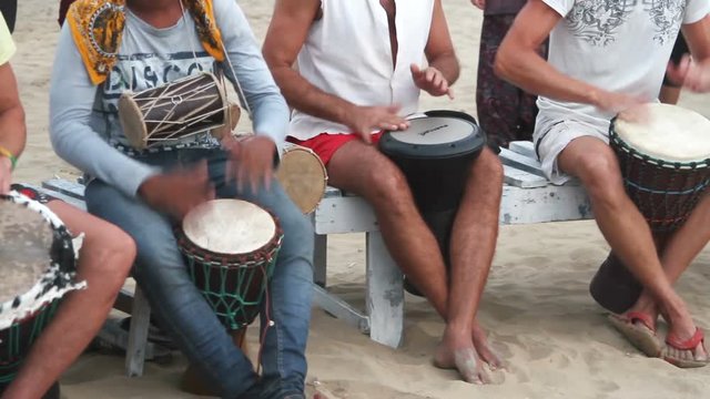 Unidentified man playing on drum at the beach. 