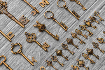 Vintage antique keys lie diagonally on a light gray wooden background