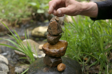 Stones balance near river  in wild nature. Human hand puts stone tower. Stones balance near river  in wild nature.