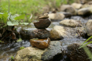 Fototapeta na wymiar Stones balance near river in wild nature. Pebbles stack by stream in forest.