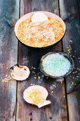 Colorful sea salt in bowls and seashells put on wooden table