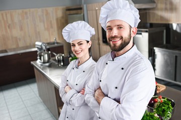 Professional team of male and female cooks standing with folded arms on kitchen - Powered by Adobe