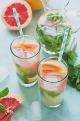Refreshment grapefruit cocktail with mint on mint color background. Healthy citrus summer drink. Toned