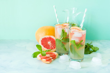 Refreshment grapefruit cocktail with mint on mint color background. Healthy citrus summer drink. Toned