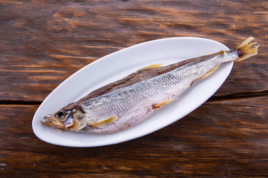 The fish dried on a white plate and a dark wooden background