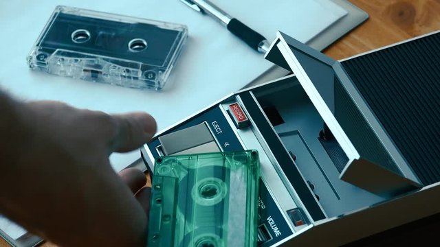 Stop and eject audio cassette from player, hand taking the tape. Vintage retro technology.