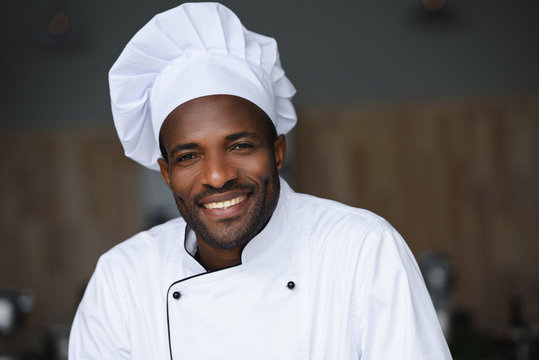 portrait of handsome african american chef looking at camera at restaurant kitchen
