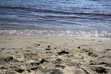 Fototapeta na wymiar Wet sand and soft waves on a beach.