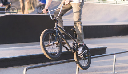 Naklejka premium Bmx Rider is doing tricks on the park skate. A cyclist slides along the rails on a BMX bike