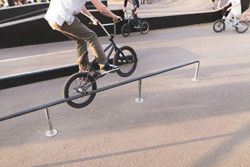 The young man performs the BMX trick on the railing in the skip box. Legs and BMX perform a trick....