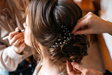Fotobehang Kapsalon Een haarstylist en visagist bereiden een bruid voor op de trouwdag  © kostyazar