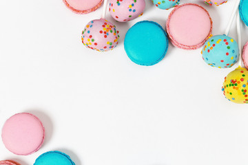 Pink and mint blue macaroons and colorful cake pops. Delicious multi-colored almond cookies as background. Copy space. Top view.