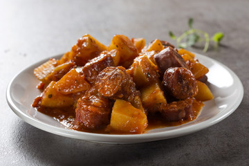 Potatoes stew with pork sausage slices and tomato sauce