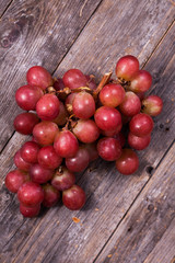 A bunch of juicy large red grapes on a table of dark old wooden boards