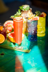 Sweet refreshing cocktails with ice of bright colors on a wooden table in the sun.
