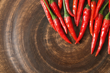 Fresh hot peppers on brown clay plate. Top view. Food background with red chili peppers with empty space for text. Homemade clay potter dish.