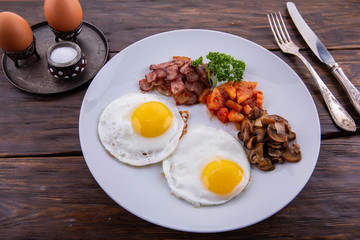 Two fried eggs with vegetables on a dark wooden background