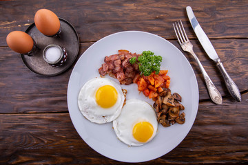 Fried eggs from two eggs with sausages, mushrooms and tomatoes