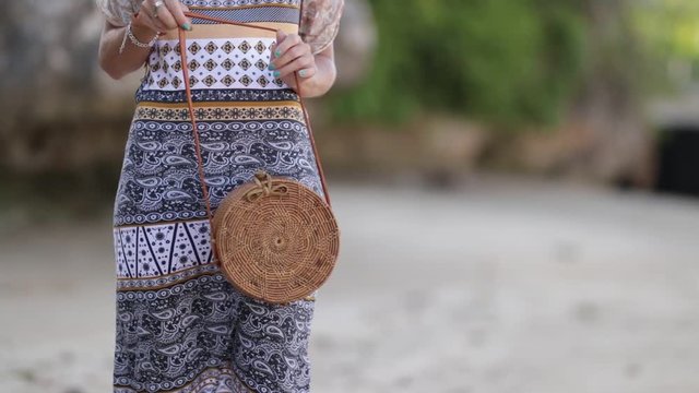Woman with fashionable stylish rattan bag on the beach. Tropical island of Bali. Handmade Rattan eco handbag HD footage.