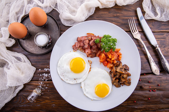 A breakfast from two eggs with the fresh tomatoes fried by mushrooms and the fried balyk
