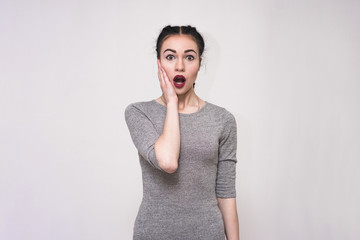 Portrait of a beautiful brunette girl on a gray background brightly showing emotions