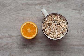 Still life healthy breakfast of muesli and orange on a wooden background. Top view.