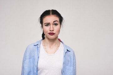 Portrait of a beautiful brunette girl on a white background showing displeasure