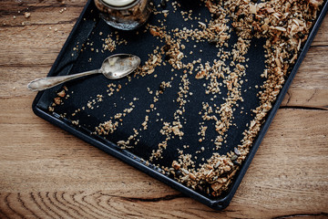 Baking tray with freshly baked homemade granola. Healthy vegan snack easily prepared at home. View from above, wooden table background.