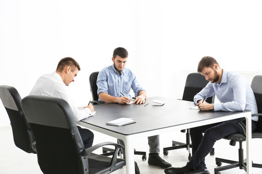 Young men sitting together at table, indoors. Unity concept