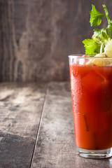 Bloody Mary cocktail in glass on wooden table.