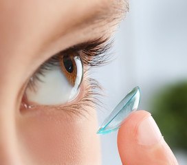 Little child putting contact lens into his eye, closeup