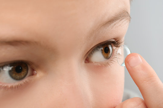 Little child putting contact lens into his eye, closeup