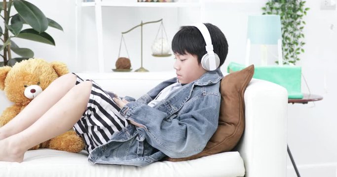 Young asian boy playing on tablet computer with headphone at home