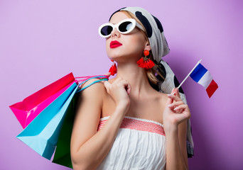 Portrait of beautiful style woman in sunglasses with french flag and shopping bags on purple...