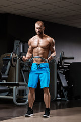 Fototapeta na wymiar Muscular strong man doing exercises with barbell in gym