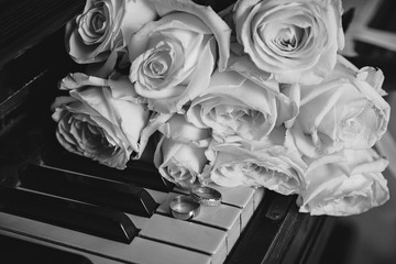 wedding rings with roses on the piano.celebration concept.black and white photo.