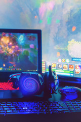 Laptop, computer, keyboard, mouse, headphones accessories for the gamer on the background of the monitor with the game, the workflow © shintartanya