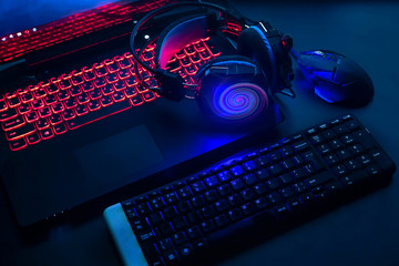 Laptop, computer, keyboard, mouse, headphones accessories for the gamer on the background of the monitor with the game, the workflow © shintartanya
