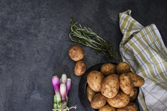 Spring onions and potatoes on dark background