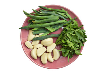Green onion, peeled garlic and parsley on a plate on a white background. Isolated