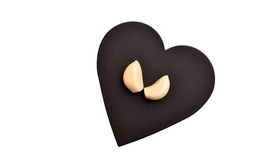 Fresh and purified garlic is on a black heart-shaped board. Isolated
